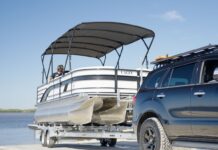 Considering Buying a Boat in Queensland? Here’s What You Need to Know Car reversing pontoon boat on trailer for beach launch while boating in Queensland