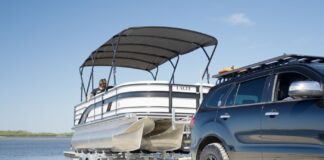 Considering Buying a Boat in Queensland? Here’s What You Need to Know Car reversing pontoon boat on trailer for beach launch while boating in Queensland