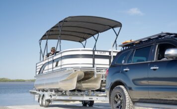 Car reversing pontoon boat on trailer for beach launch while boating in Queensland